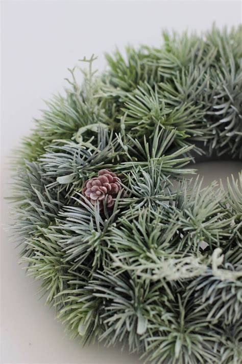 detailná fotografia zasnežených vetvičiek so striebornými guľami a prírodnými šiškami