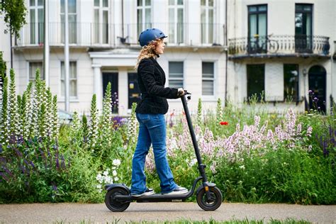Muž jazdiaci na elektrickej kolobežke v meste, s rozostreným pozadím