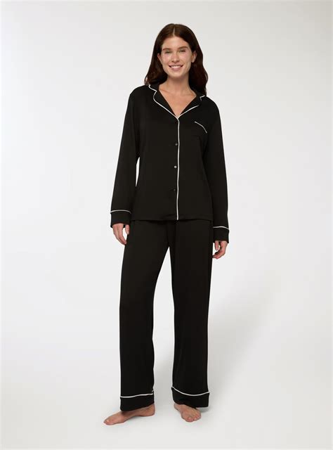 Ženích v tehlových trakoch a motýliku s tmavými nohavicami a bielou košeľou na pozadí statku