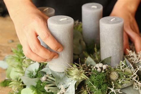 Fotografia moderného adventného venca s netradičnými prvkami, ako sú zafarbené cestoviny a sviečky.