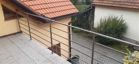 Nočný pohľad na vysvietený balkón s malým vianočným stromčekom a svetelnými reťazami na zábradlí