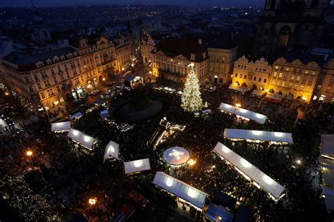 Pohľad na vianočne vyzdobené Horné námestie v Olomouci s historickou radnicou a osvetlenými stánkami.