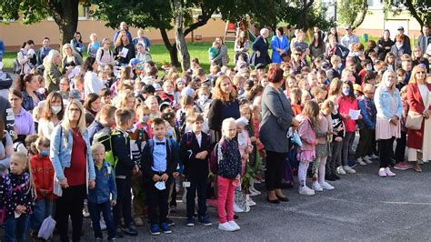 Tematická fotografia: riaditeľka školy s mikrofónom víta žiakov a rodičov na školskom dvore