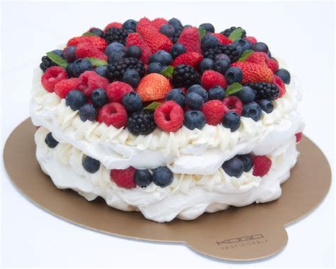 Elegantná Pavlova torta s bielou snehovou pusou, šľahačkou a čerstvým lesným ovocím.