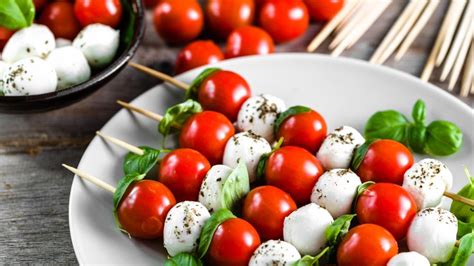Tanier s rôznymi svadobnými predjedlami, ako sú plnené rolky, caprese špízy a mini tartaletky