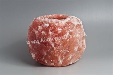 Detailný záber na vysoký himalájsky solný svietnik s horiacou čajovou sviečkou, vyžarujúci teplé oranžové svetlo v modernom interiéri