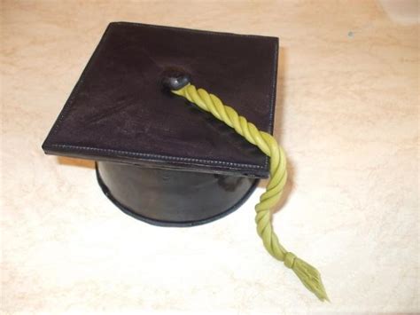 Tematické foto: Ruka držiaca diplom a promočnú čiapku s hromadou kníh v pozadí