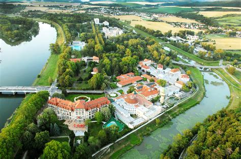 Záber na Kúpeľný ostrov v Piešťanoch s historickými budovami a udržiavaným parkom.