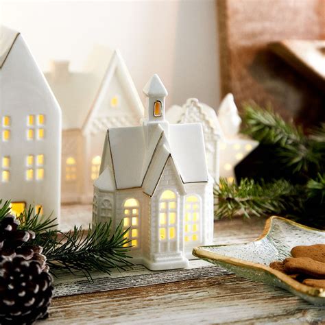 Kolekcia bielych vianočných dekorácií: Santa, anjel, porcelánový domček a sviečka.
