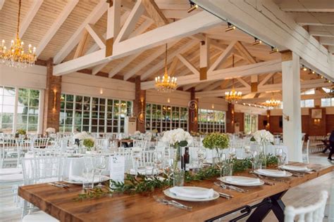 Elegant wedding setup in a rustic restaurant hall with wooden elements, decorated with flowers.