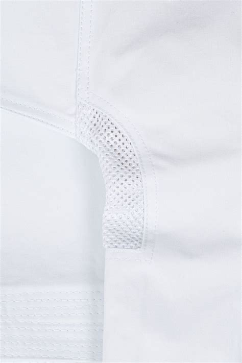 detailná fotografia bielej krstnej košieľky s modrou výšivkou mena a krížika