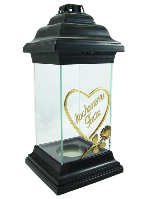 Detailný záber na zapálené sviečky na hrobe, obklopené chryzantémami.