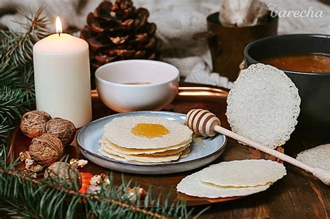 Zátišie so symbolickými predmetmi: vianočné oblátky, med, cesnak, jablká a orechy na sviatočnom stole.
