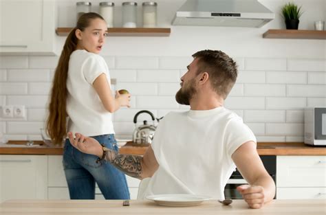 Muž v kuchyni s personalizovanou zástrou a koženými rukavicami