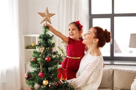 Rodina zdobí vianočný stromček s darčekmi pod ním