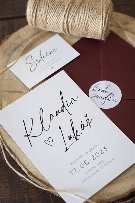 Detail svadobného oznámenia s ručne kreslenými kvetinovými motívmi a saténovou stuhou.