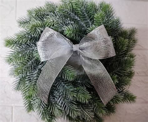 Detail striebornej mašle na zelenej vetvičke vianočného stromčeka