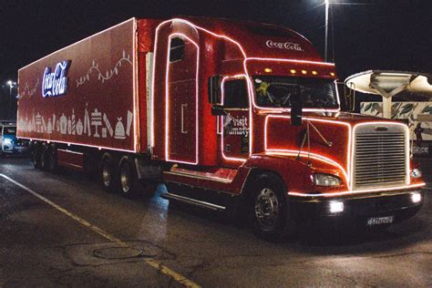 Vianočne vyzdobený červený kamión Coca-Cola osvetlený tisíckami svetielok na námestí