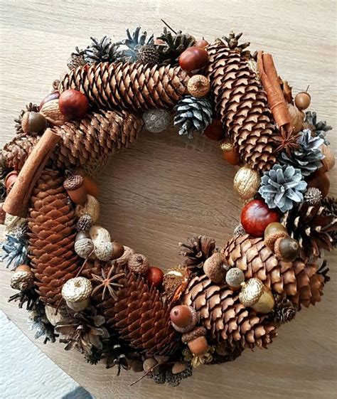 Detailný pohľad na adventný veniec zo šišiek s pridanými prírodnými ozdobami.