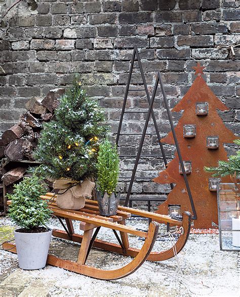 Fotografia vchodu do domu s vianočnými dekoráciami vrátane vázy a postavičky.