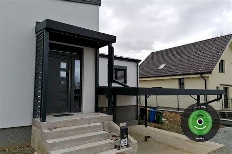 Záber na útulne vyzdobený vchod do domu s vianočným vencom, lucernami a čečinou v kvetináčoch
