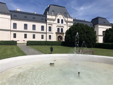 Záber na historickú architektúru zámku obklopenú udržiavaným parkom a zeleňou.