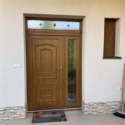 Záber na vchodové dvere domu vyzdobené v rustikálnom vidieckom štýle s vencom z čečiny a teplým osvetlením