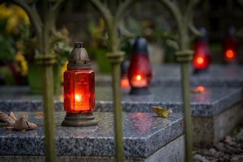 Ilustrácia zobrazujúca tradičné slovenské Dušičky s horiacimi sviečkami na hroboch a rodinami pripomínajúcimi si svojich zosnulých.