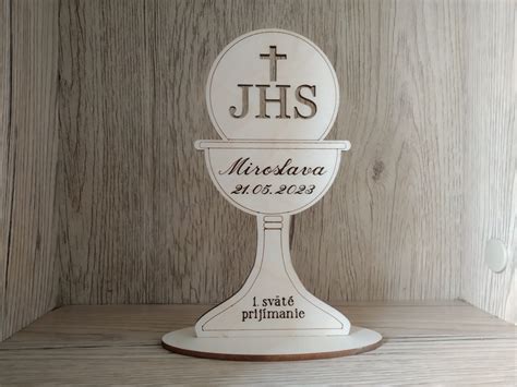 Detailný záber na prijímanie Eucharistie, zameraný na hostiu a kalich.
