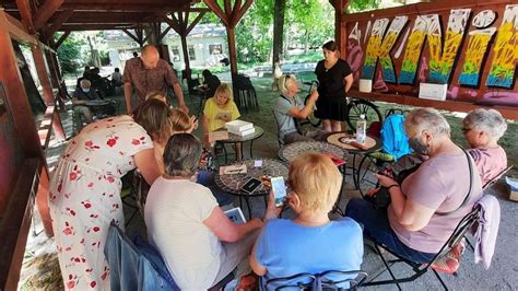 Fotografia letnej čitárne v Medickej záhrade s ľuďmi čítajúcimi knihy