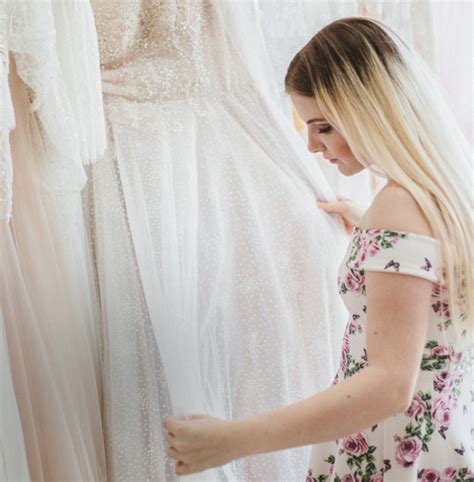 Tematické foto nevesty skúšajúcej svadobné šaty v salóne, s asistentkou