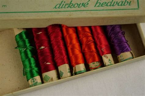 Ukážka rôznych štýlov vyšívaného písma a farebných kombinácií nití na bavlnenom textile.