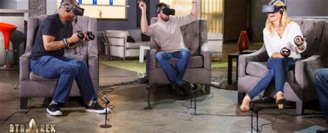 Ľudia hrajúci VR hru, s okuliarmi a ovládačmi, vo futuristickom prostredí.