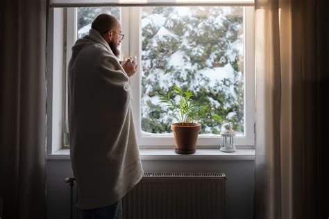 Tematické foto: Osoba s melancholickým výrazom, pozerajúca sa z okna v zimnom období