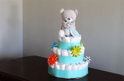 Schéma zloženia poschodovej plienkovej torty s ozdobnými stuhami a hračkami