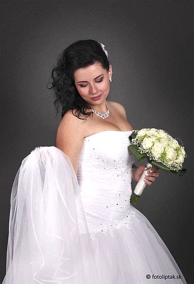 Svadobná fotografia, kde nevesta drží krémovú kyticu s jemnými zelenými prvkami.