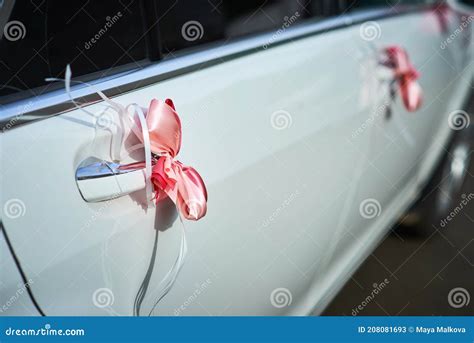 Photo of white bows and ribbons on car door handles and side mirrors