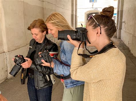 Tematické foto: Žena na fotografickom kurze držiaca zrkadlovku a usmievajúca sa.