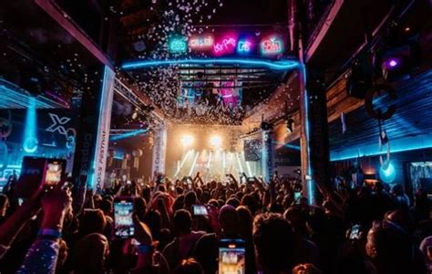Páry pri socializácii na tematickej swingers party v klube, s miernym osvetlením a hudbou