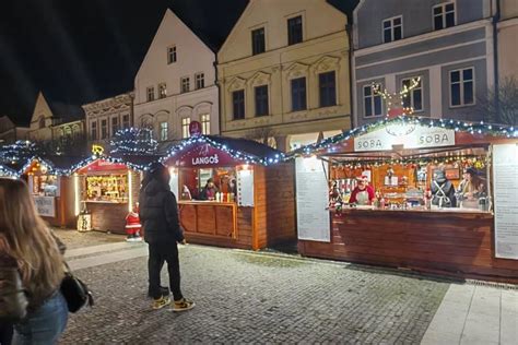 rozprávková atmosféra vianočných trhov, ľudia v dave, osvetlené stánky