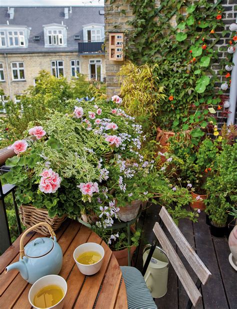 Záber na štýlovo zariadený balkón plný rozkvitnutých kvetov v rôznych kvetináčoch a hrantíkoch