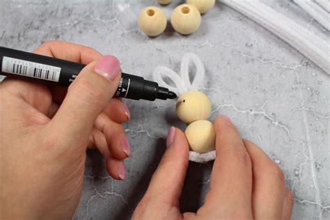 Ilustrácia postupných krokov výroby zajačika z drôtu a korálok, zobrazujúca stočenie drôtu do tvaru srdca, pridanie korálok na uši a finálne dotvarovanie.