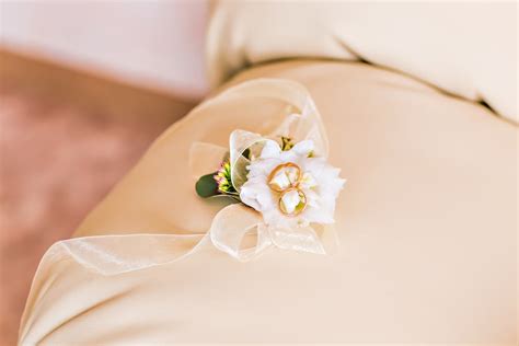 Detailná fotografia svadobných obrúčok na kytici nevesty v jemnom svetle.