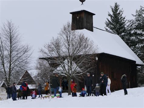 Zasnežená dedina v čase Vianoc s osvetlenými oknami, symbolizujúca pokoj a rodinnú súdržnosť.