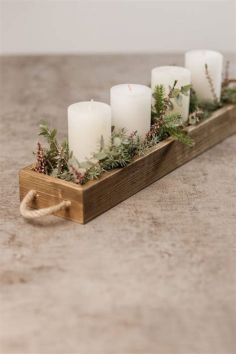 Štýlový drevený svietnik ozdobený konármi a škoricovými tyčinkami.