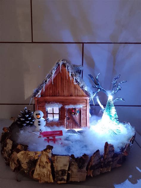 Svietiaca drevená dekorácia do okna s pohármi na sviečky, šišky a konáre.