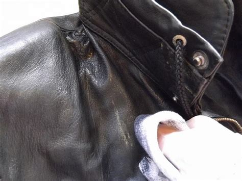 Detailná umelecká čierno-biela fotografia nevesty v koženej bunde so svadobnou kyticou pri motorke