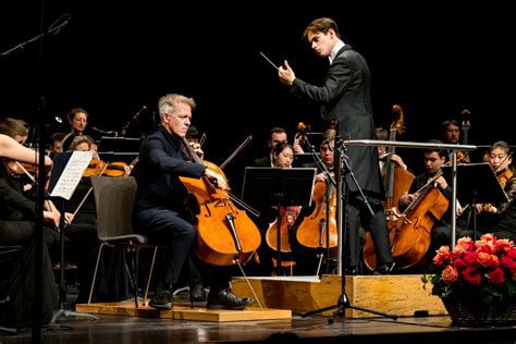 Tematická fotografia: Dirigent na pódiu vedie orchester, operní speváci spievajú