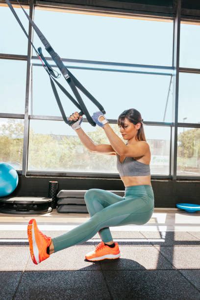 Žena cvičiaca s kettlebellom a TRX systémom v posilňovni