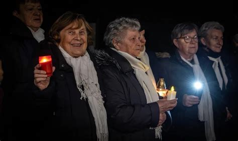 Skupina ľudí spieva koledy pri dome